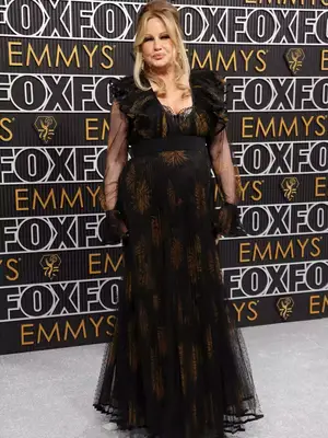 Jennifer Coolidge wears a black lace gown with gold pattern and glam updo to the January 2024 Emmy Awards