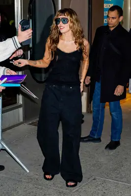 Miley Cyrus out in New York City wearing an all-black outfit, wavy hair, and baby bangs.