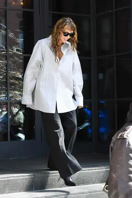 Miley Cyrus out in New York City wearing an oversized button up shirt, wavy hair, and baby bangs.