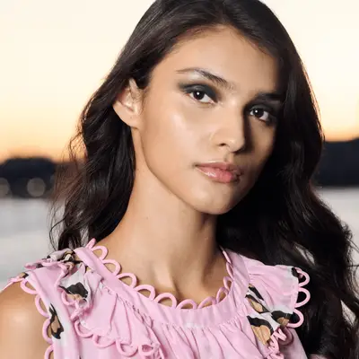 Model in a pink shirt and shimmery green eyeshadow