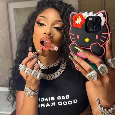 Megan Thee Stallion mirror selfie applying lipgloss and showing off multi-color iridescent nails