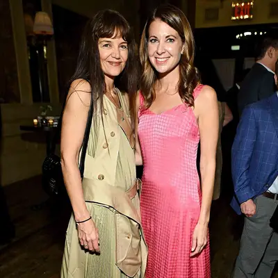 Katie Holmes with brown blunt bangs and a trench-coat dress