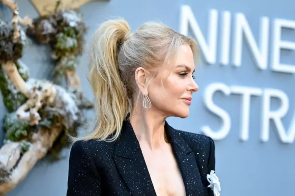 Nicole Kidman poses on the red carpet wearing a black suit and voluminous ponytail.