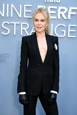 Nicole Kidman poses on the red carpet wearing a black suit and voluminous ponytail.