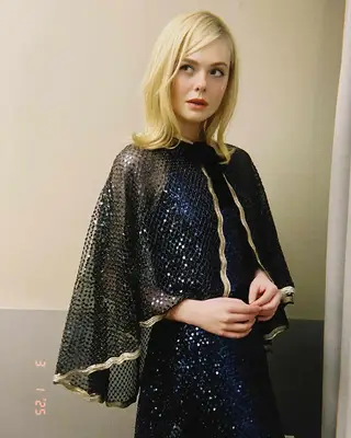 Elle Fanning wearing an ornate outfit, looking to the side