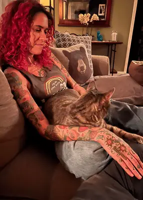 woman sitting with cat in lap to show tattoo sleeve