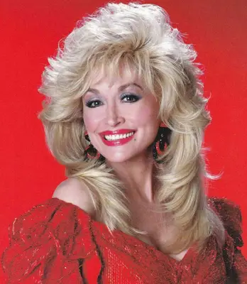 Dolly Parton wears pastel blue eyeshadow and glossy red lipstick
