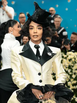 Tessa Thompson wearing fluffy bob with suit dress and black top hat