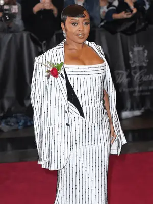 Quinta Brunson wearing sleek pixie cut and white and black dress with an overcoat
