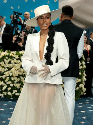 Kerry Washington wearing cream dress with plunging neckline and top hat and texture bubble ponytail