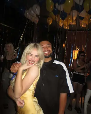 Sabrina Carpenter wearing a yellow dress with a guest at her 25th birhday party.