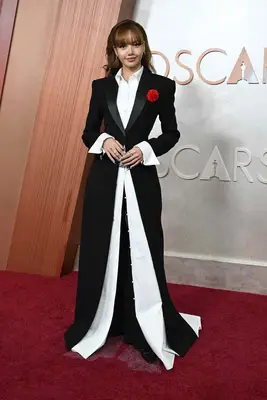 Lisa wears. a black and white Markgong ensemble with red corsage to the 2025 Oscars