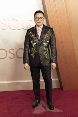Bowen Yang wears a black suit with embroidered jacket and pink suit to the 2025 Oscars
