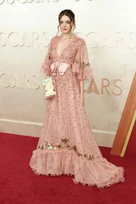 Charlotte Lawrence wears a bedazzled pink gown and cat purse to the 2025 Oscars