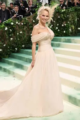 Pamela Anderson wears a nude tulle Oscar de la Renta gown and feathered hairpiece to the 2024 Met Gala