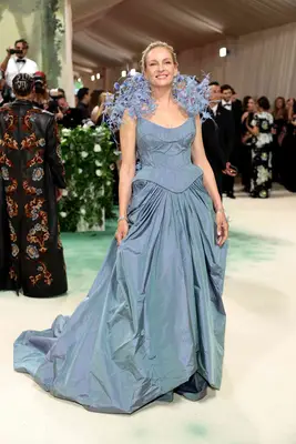 Uma Thurman wears a blue gown with corseted bodice, voluminous skirt, and artful floral shoulders to the 2024 Met Gala