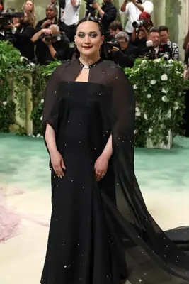 Lily Gladstone wears a black gown and cape with star embroidery and a braided hairstyle to the 2024 Met Gala