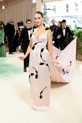 Lily James wears a pastel pink Erdem gown with train and black flower appliques to the 2024 Met Gala