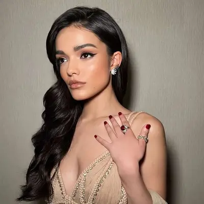 Rachel Zegler in a hooded tan gown, 