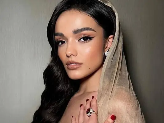 Rachel Zegler in a hooded tan gown, 