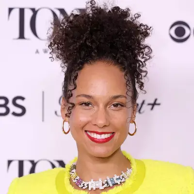 alicia keys in yellow top with gold hoop earrings, red lipstick and curly updo