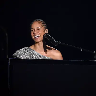 alicia keys in silver top with braided hair in front of black microphone and piano