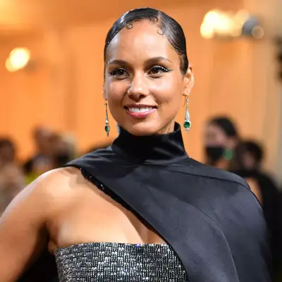 alicia keys with black high neck top, diamond and emerald earrings, and slicked back hair