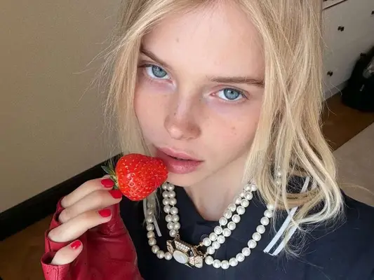 Model Alla Bruletova shows off her milkshake blonde hair color by Nicole Kahlani while eating a strawberry.