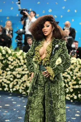 Cardi B poses on the red carpet at the 2025 Met Gala, showing off her green velvet manicure and matching suit.