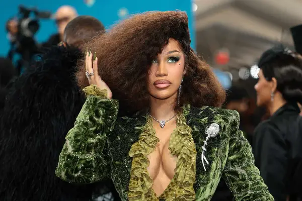Cardi B poses on the red carpet at the 2025 Met Gala, showing off her green velvet manicure and matching suit.