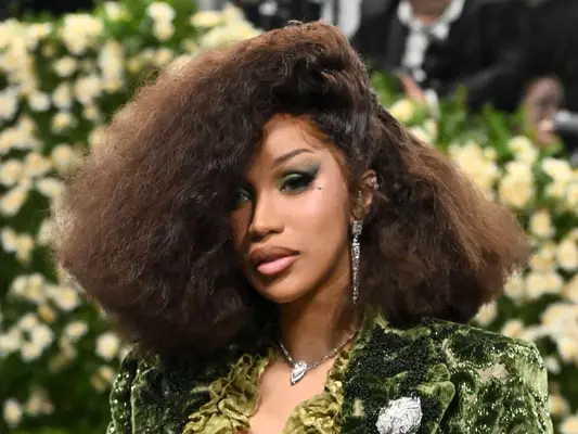 Cardi B poses at the 2025 Met Gala with her hair in an asymmetrical afro and a green velvet Burberry suit.