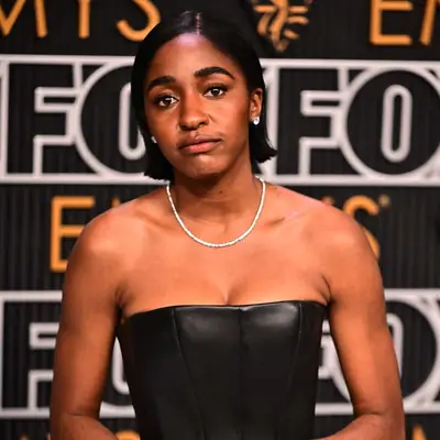 Ayo edebiri with a malt shop flippy bob, black dress, and cherry mocha nails