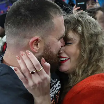 Taylor swift with sparkling rose wine nails and red lipstick hugging travis Kielce at the AFC championship
