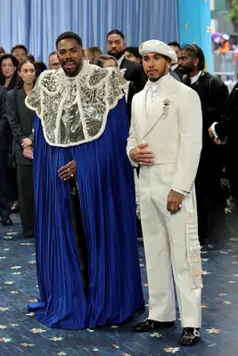 Colman Domingo in a blue adorned cape and Lewis Hamilton in a white well-tailored suit and hat at the 2025 Met Gala