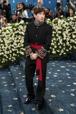 Barry Keoghan wears a black military suit with embroidery and red belt to the 2025 Met Gala
