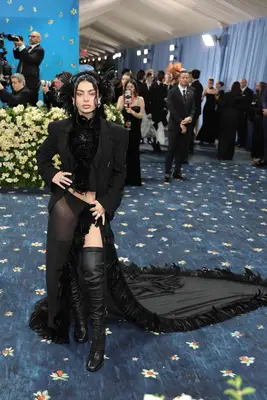 Charli XCX wears a black suit jacket, sheer feather trim skirt, and boots to the 2025 Met Gala