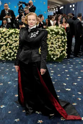 Sarah Snook wears a tailored jacket, drape train with red accents, brooches, and bow tie to the 2025 Met Gala
