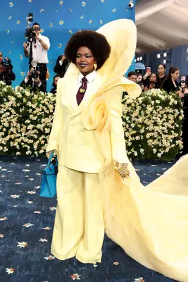 Lauryn Hill wears a butter yellow structural suit and blue handbag to the 2025 Met Gala