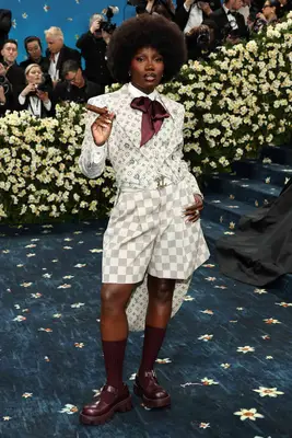 Doechii wears a patterned gray and cream Louis Vuitton shorts suit with oxblood tie and Mary Janes to the 2025 Met Gala