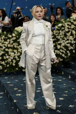 Madonna wears a cream-colored full silky suit and low ponytail hairstyle to the 2025 Met Gala