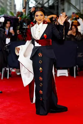 Mindy Kaling wears a navy maxi skirt suit with red and white lapels and cummerbund plus statement buttons