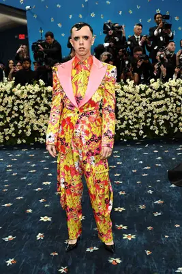 Cole Escola wears a pink and yellow Christopher John Rogers suit, black pumps, and dramatic lashes to the 2025 Met Gala