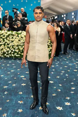 Jeremy Pope wears a beige sleeveless top and black tailored trousers to the 2025 Met Gala