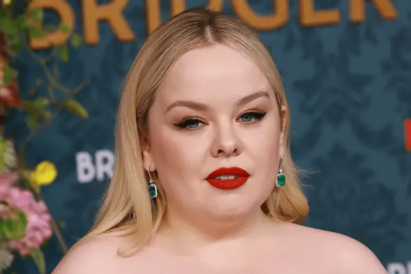 A close up of Nicola Coughlan wearing a bold red lip.