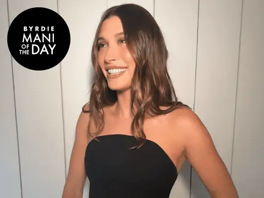 Hailey Bieber smiling in a black dress