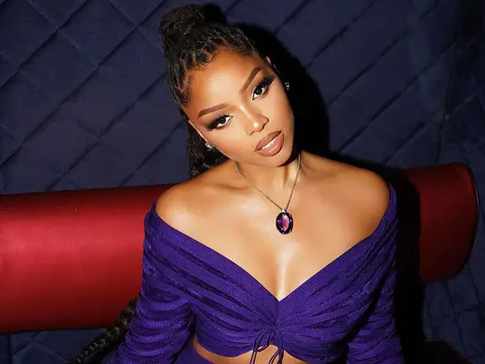 Chloe Bailey in an off the shoulder purple top and ponytail