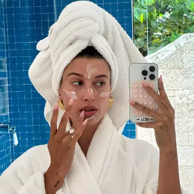 Hailey Bieber in a bathrobe and lip gloss nails