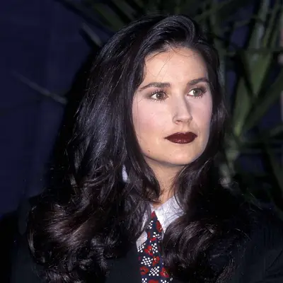Demi Moore with a voluminous blowout and dark berry lip.
