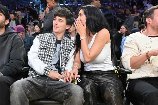 Kylie Jenner whispers to Timothee Chalamet while sitting courtside at a basketball game.