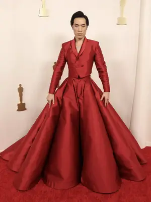 Eugene Lee Yang wears a red tailored jacket and ball skirt to the 2024 Oscars